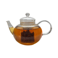 Teekanne aus Glas mit flüssigem Assam Schwarztee und losen Schwarzteeblättern