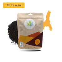 Der Geheimtipp Assam Boost Tee Verpackung aus Papier mit losem Assam Chadwar Schwarztee im Hintergrund