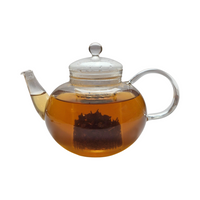 Teekanne aus Glas mit flüssigem Erdbeere Rhabarber Schwarztee und losen Schwarzteeblättern