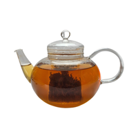 Teekanne aus Glas mit flüssigem Darjeeling Schwarztee und losen Schwarzteeblättern