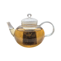 Teekanne aus Glas mit flüssigem Himbeere Minze Grüntee und losen Grünteeblättern