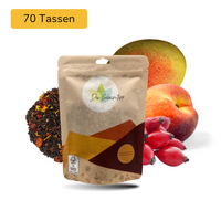 Der Geheimtipp Mango Peach Party Tee Verpackung aus Papier mit losem Mango Pfirsich Schwarztee im Hintergrund