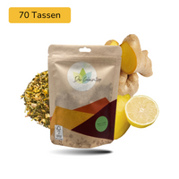 Der Geheimtipp Spicy Lemon Tee Verpackung aus Papier mit losem Ingwer Zitrone Grüntee im Hintergrund